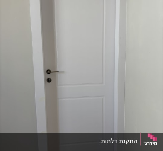 דלת לבנה עם ידית מתכת בחדר
